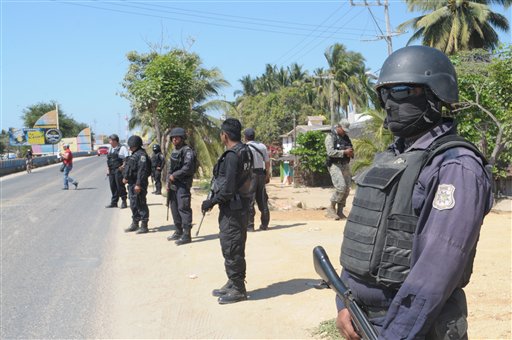State police stand Tuesday at a roadblock in Acapulco, Mexico, implemented as part of stepped-up security efforts after masked armed men broke into a beach home, raping six Spanish tourists who had rented the house.