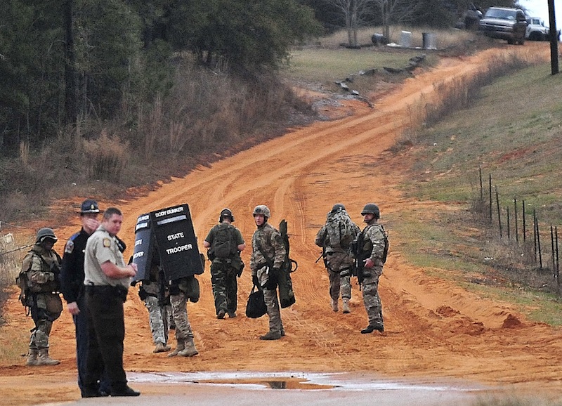 Law enforcement personnel work at check point Wednesday, Jan. 30, 2013, in Midland City, Ala., near the home where the Tuesday's school bus shooting suspect is barricaded in a bunker with a young child as hostage. Police, SWAT teams and negotiators were at a rural property where a man was believed to be holed up in a homemade bunker Wednesday after fatally shooting the driver of a school bus and fleeing with a 6-year-old child passenger, authorities said. (AP Photo/The Dothan Eagle, Jay Hare) BUS SHOOTING;MIDLAND CITY