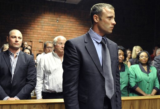 Oscar Pistorius stands following his bail hearing, as his brother Carl, left, and father Henke, second from left, look on in Pretoria, South Africa, on Tuesday.