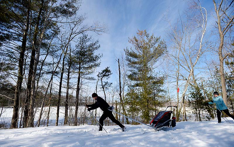 Chris and Kim Nichols of Scarborough cross-country ski along the Eastern Trail in Scarborough on Sunday. Chris is pulling his 9-month-old daughter, Lily, in a tow on skis.