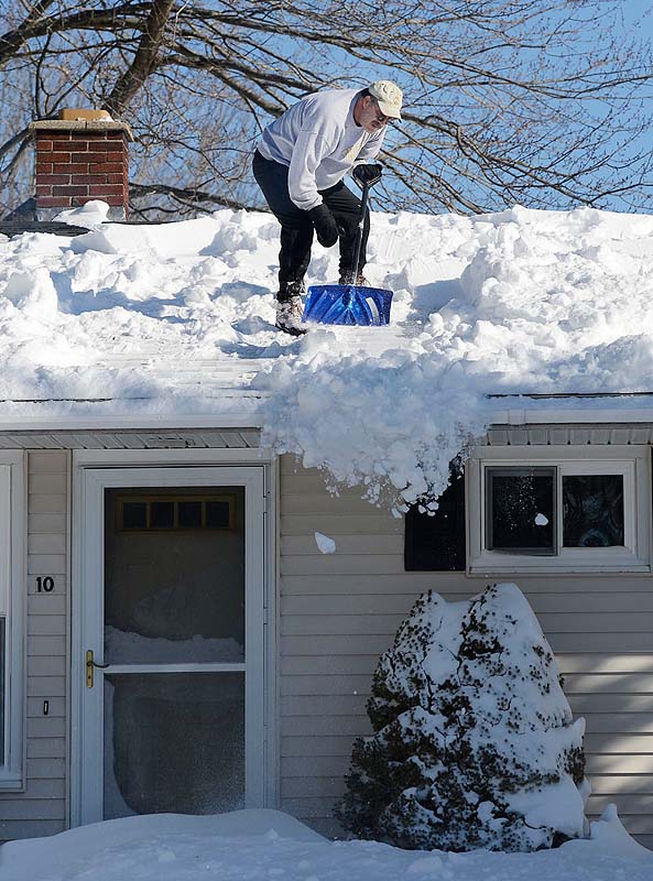 Kevin McPherson of Pleasant View Drive in Saco shovels off his roof on Sunday.