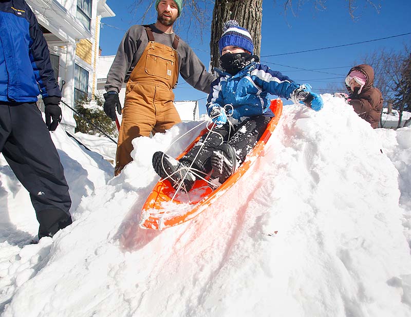 Charlie Creswell, 4, sleds down a hill created by the snowplows on Fessenden Street in Portland on Sunday.