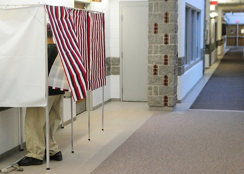 A voter fills out an absentee ballot in a voting booth in the hallway near the Augusta city clerk's office.