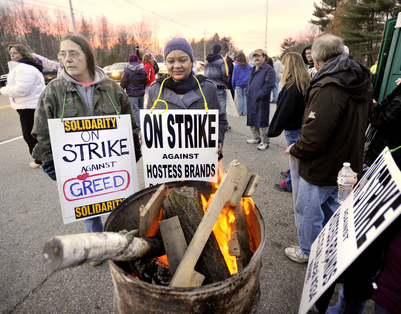 Photo by John Ewing/staff photographer... Striking Hostess Brands workers in Biddeford warm up at a fire barrel while walking on the picket line in this November 15 2012 file photo. About 370 workers at the company's bakery in Biddeford lost their jobs when the plant closed last November.
