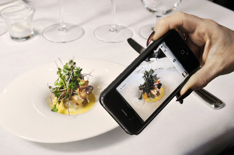 A diner uses her iPhone to photograph a serving of butter-poached lobster risotto at David’s Opus Ten in Portland’s Monument Square.