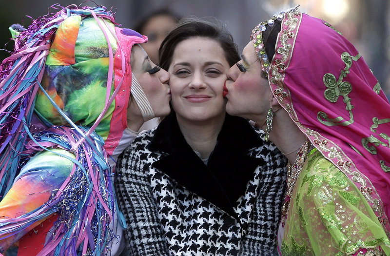 Actress Marion Cotillard of France, center, the Hasty Pudding Woman of the Year, is kissed by Harvard University theatrical students Renee Rober, left, and Ben Moss during a parade through Harvard Square on Thursday.