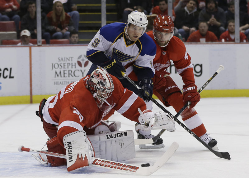 Detroit goaltender Jimmy Howard reaches for the puck while teammate Jakub Kindl guards against St. Louis center Jaden Schwartz during Friday’s NHL game in Detroit, won by the Red Wings.