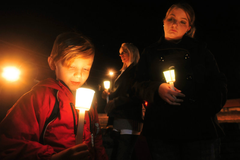 Cade Smith, 6, holds a candle as his mother, Brandi, looks on during a candlelight vigil Friday in Midland City, Ala.