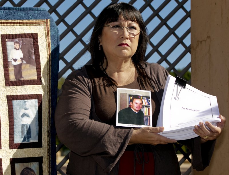 Esther Miller, 54, who says she was abused by the Rev. Michael Nocita, seen in middle picture, holds newly released files on Nocita, at a news conference Friday held by the Survivors Network of those Abused by Priests outside the Cathedral of Our Lady of the Angels in Los Angeles.