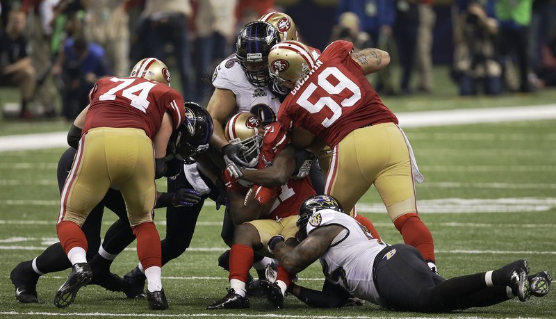 San Francisco running back Frank Gore, center, is tackled by Baltimore’s Terrell Suggs, right, and Ma’ake Kemoeatu. Gore rushed for 110 yards and a touchdown, but the 49ers’ second-half comeback bid fell short.