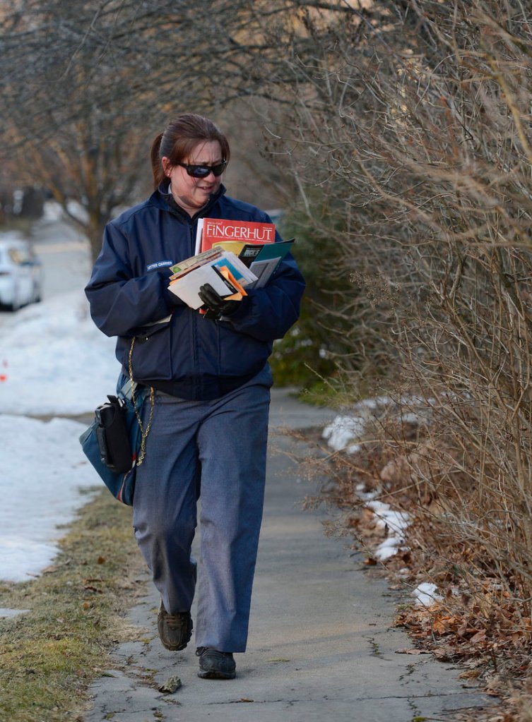 Mail carrier Carrie Estes sorts through mail on Bradley St. in Portland during her delivery route Wednesday, February 6, 2013. The U.S. Postal Service will stop delivering mail on Saturdays in an effort to save about $2 billion annually.