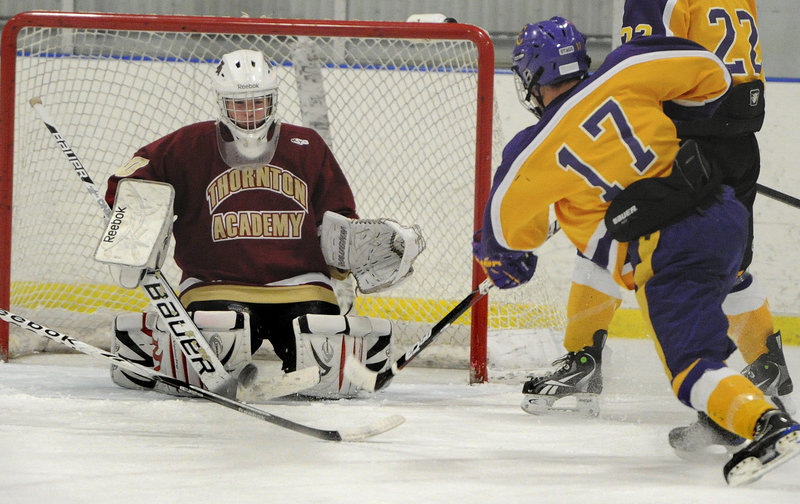 Thornton goaltender Andy Huot drops to his knees to block a shot by Cheverus’ Jimmy Hannigan during Thursday’s game at the Portland Ice Arena.