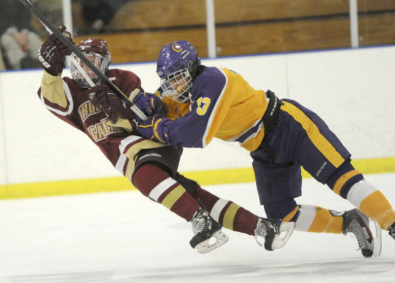 Thornton Academy’s Cooper O’Brien goes down following a check by Cheverus’ Andrew MacGillivray during Thursday night’s high school hockey game at the Portland Ice Arena, won by Cheverus, 3-2.