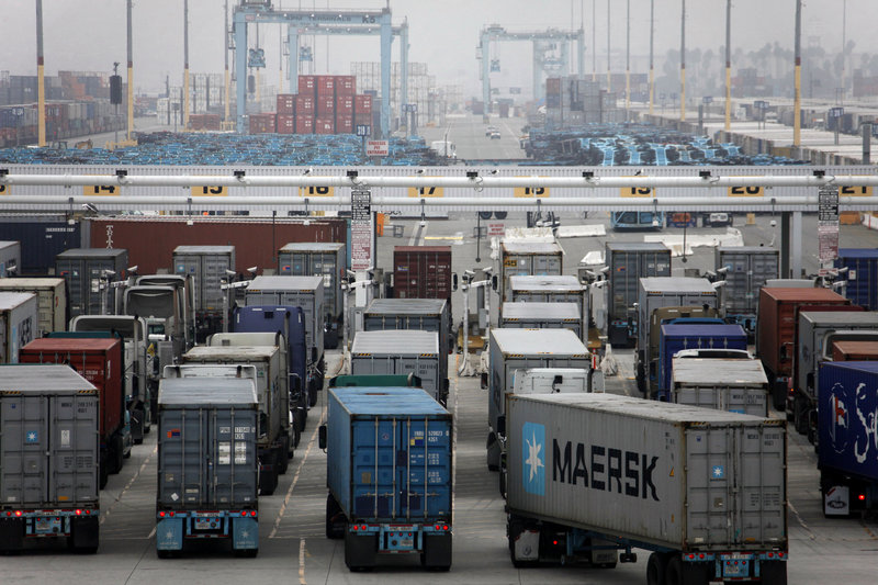 Trucks wait to be loaded at the Port of Los Angeles in December. A separate Commerce Department report Friday showed wholesale stockpiles declined in December, which could offset some of the gain from trade.