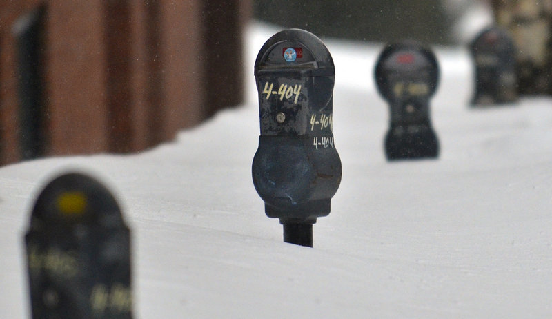Parking meters on Market Street in Portland are nearly covered in snow after a blizzard Feb. 9.