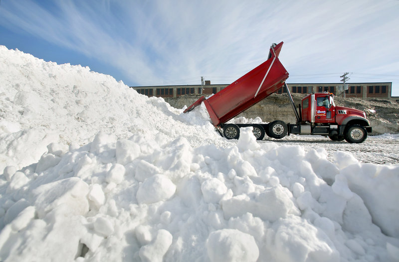 A truck dumps a load of snow in a lot at Preble and Kennebec streets in Portland on Sunday during the cleanup in the aftermath of the weekend blizzard that set a record of 31.9 inches of snowfall in the city.