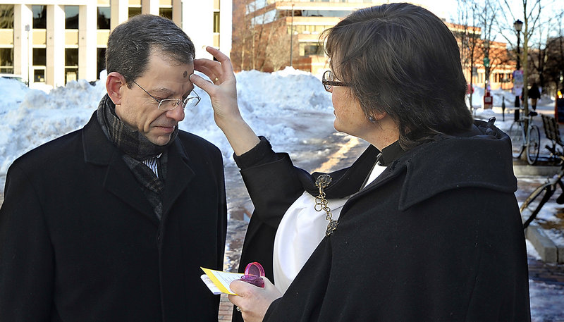 Mike Watson of Cape Elizabeth gets ashes from Suzanne Roberts, a deacon at St. Luke’s, on Ash Wednesday in Portland’s Monument Square.