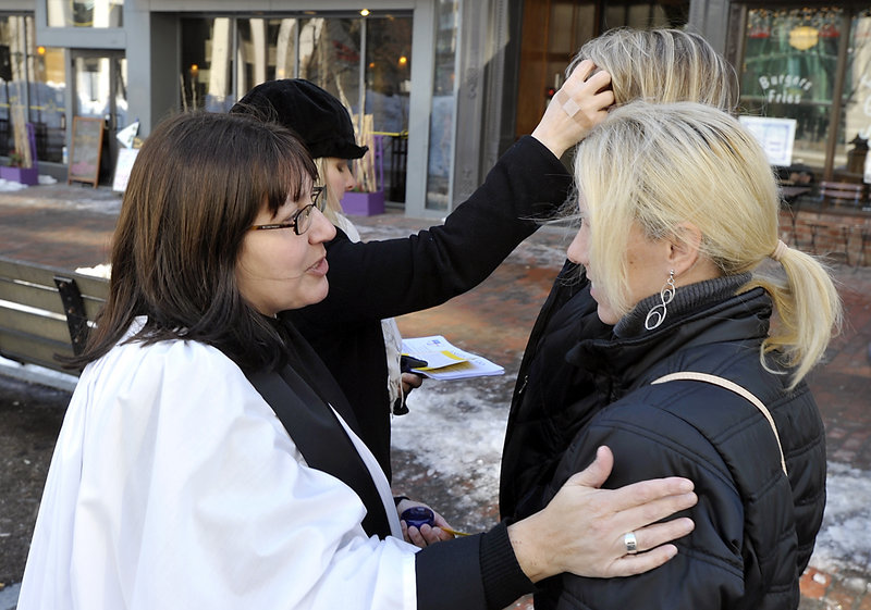 Nina Pooley, left, talks with Kristine Taylor of Portland after putting the ashes on her forehead as Gwen DeCicco, left rear, puts ashes on the forehead of Suzanne Parent of Portland.