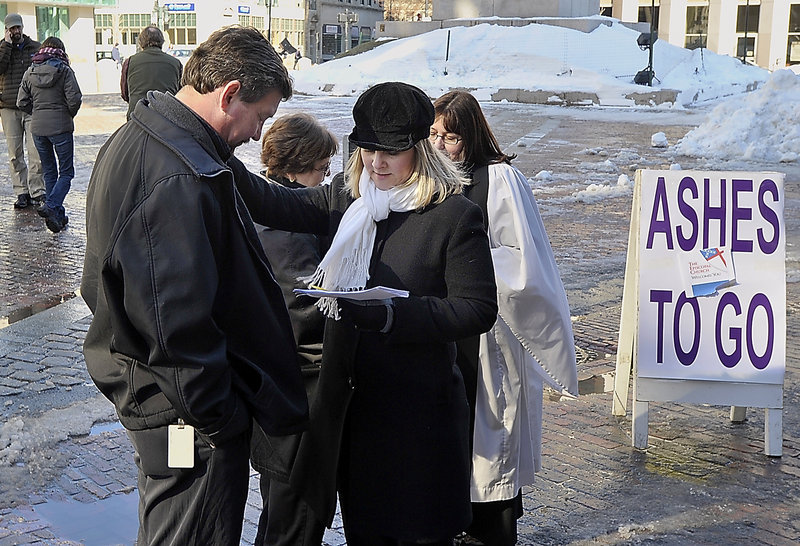 Randy LeShane of Windham and his mother, Gale Murphy, get ashes Wednesday from Gwen DeCicco, a lay person at the Cathedral Church of St. Luke in Portland, and Nina Pooley, a rector at St. Bartholomew’s Episcopal Church in Yarmouth.
