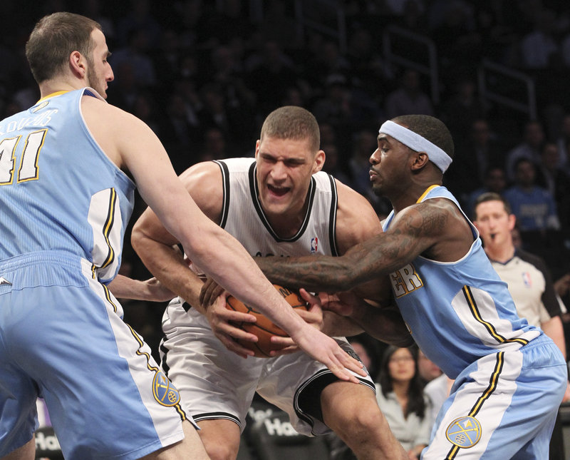 Brooklyn’s Brook Lopez fights for a loose ball against Denver’s Kosta Koufos, left, and Ty Lawson during the Nets’ 119-108 win over the Nuggets at New York on Wednesday.