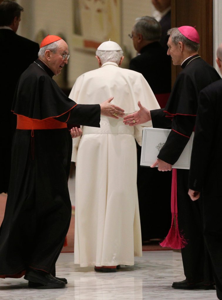 Cardinal Agostino Vallini, left, and the pope’s personal secretary, Georg Gaenswein, shake hands as Pope Benedict XVI leaves after an audience with Roman clergy Thursday.