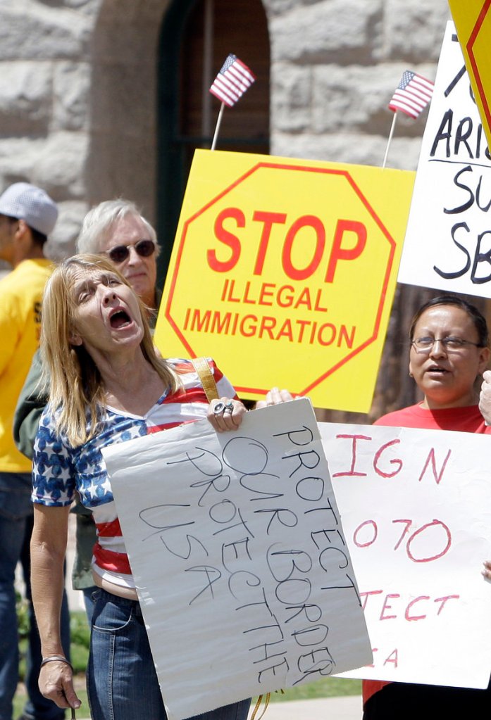 Supporters rally in Phoenix just before Arizona Gov. Jan Brewer signed a tougher immigration bill into law on April 23, 2010. The Democratic Party and Big Business are conspiring in favor of lifting immigration limits “to keep America flooded with low-wage labor,” a reader says.