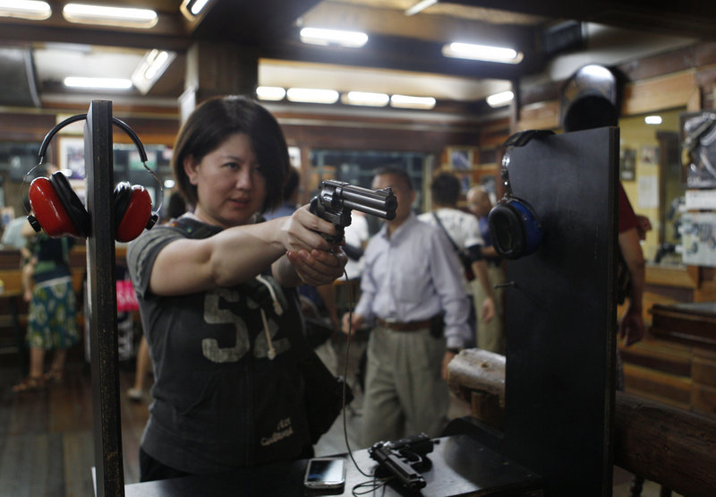 Japanese tourist Natsue Matsumoto, 38, takes aim at an indoor shooting range in Guam, where shooting is a popular tourist activity. The small U.S. territory attracts visitors who typically have little access to firearms in their own country.
