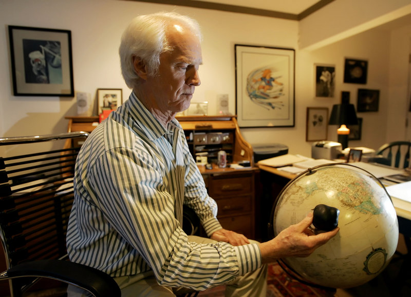 Former Apollo astronaut Rusty Schweickart holds a model of an asteroid over a globe in 2005 to demonstrate the devastation such an impact would have.