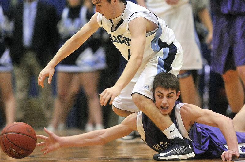 Jordon Derosby of Waterville dives for a loose ball and reaches through the legs of Jonah Stephenson of Presque Isle on Saturday in Bangor. Presque Isle won the Eastern Class B quarterfinal, 47-45.