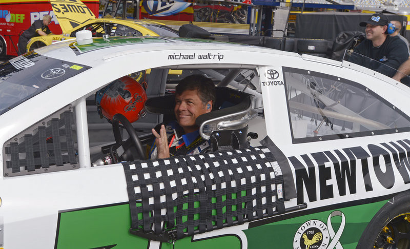 Michael Waltrip waves to fans as his crew pushes his car through the garage area Saturday during practice for the Daytona 500 at Daytona International Speedway. Pole qualifying is Sunday, and the race is next Sunday.