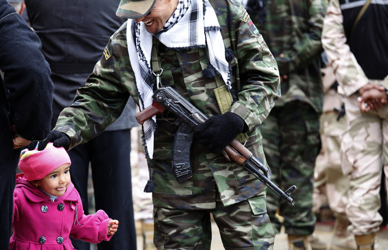 A member of the Libyan security forces pats a child while celebrating the revolution’s anniversary in Benghazi, on Sunday. In their new society, Libyans are impatient for “transitional justice.”