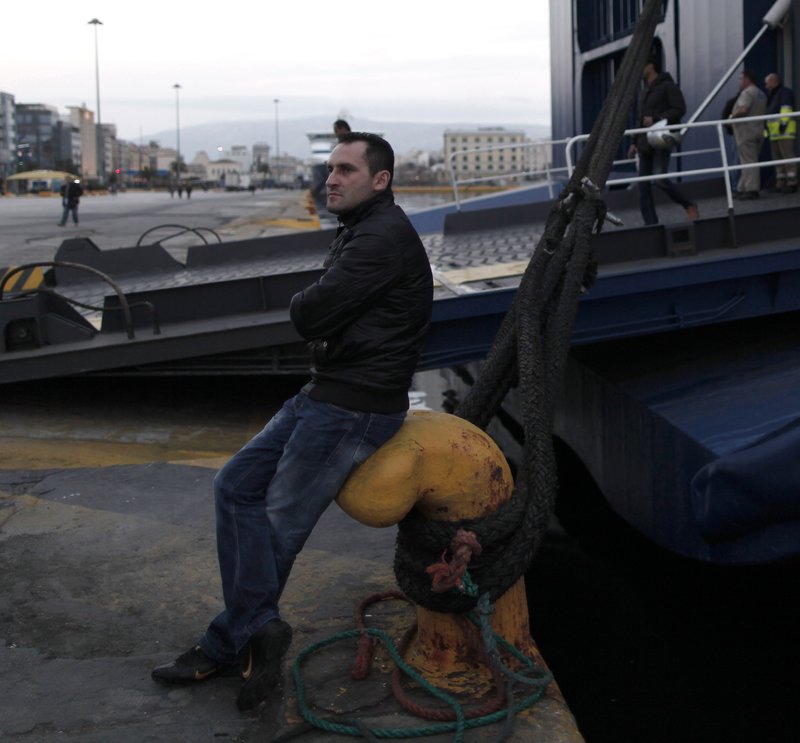 An unpaid striking dock worker sits next to an idle ferry at the port of Piraeus near Athens. Researchers from Greece’s largest labor union, the GSEE, say nearly two-thirds of private sector employees no longer get paid regularly, while facing government demands for higher taxes.