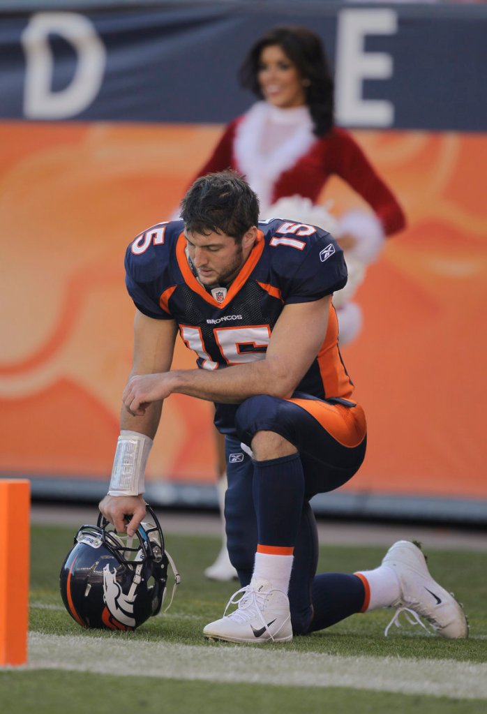Then-Denver quarterback Tim Tebow prays on the sideline during a 2012 playoff game.