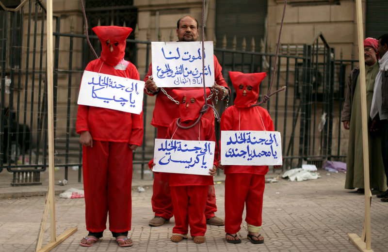An Egyptian man and his three children wear red during a symbolic hanging at an anti-government protest in front of Egypt’s high court building in downtown Cairo on Friday.