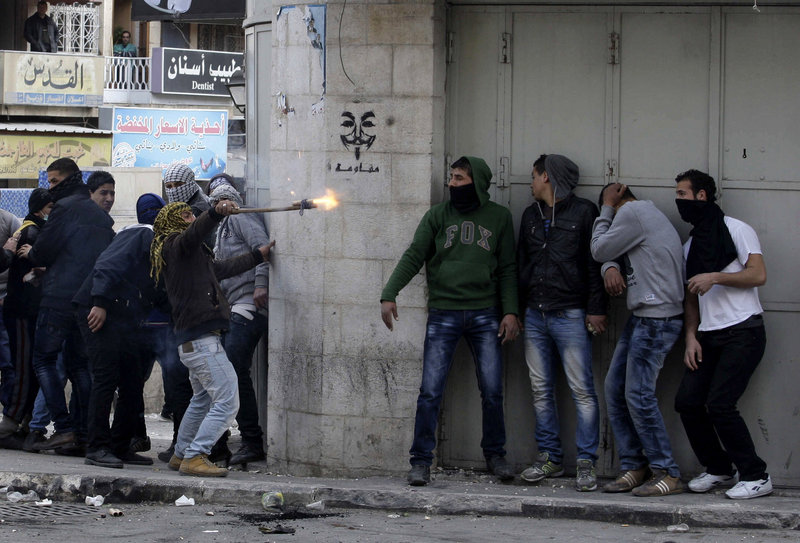 Palestinians take cover during clashes with Israeli troops in the West Bank city of Hebron on Sunday, following the death of Arafat Jaradat, a Palestinian prisoner held in an Israeli prison.