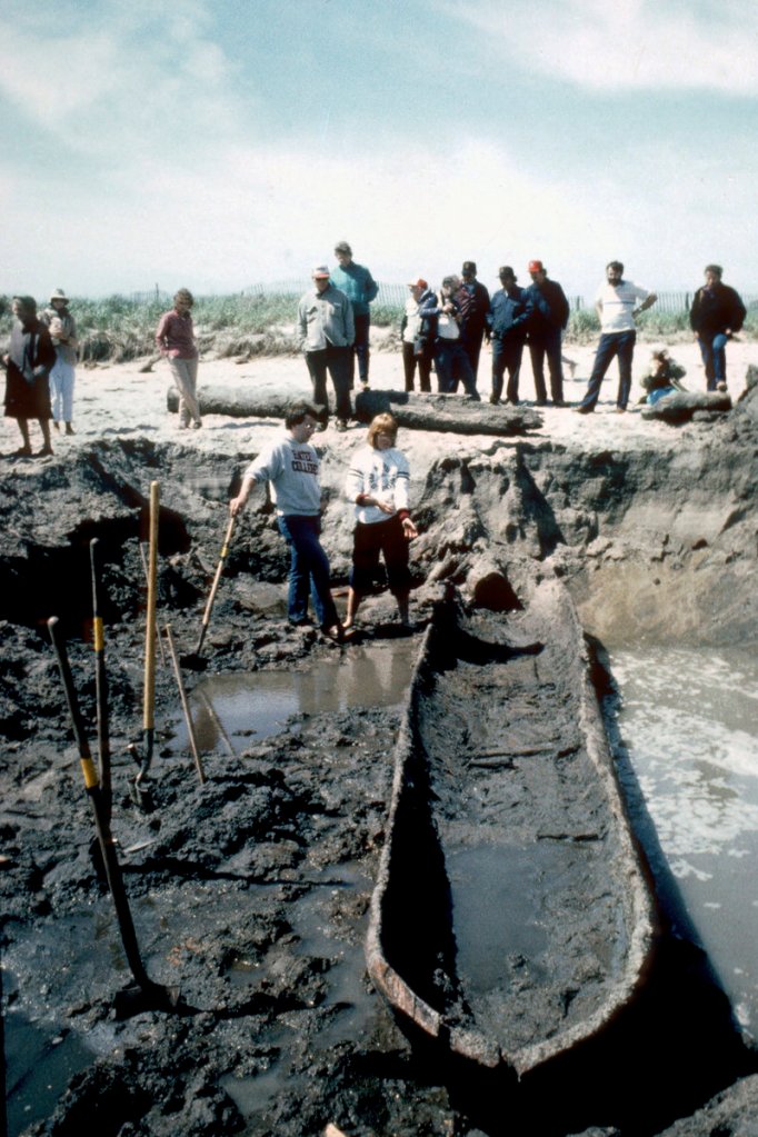 Volunteers Kirk Upton, front left, and Christine Styrna stand near a dugout canoe as it is excavated from a beach in Biddeford Pool on June 4, 1986. The canoe, believed to be from the eighteenth-century and made by early settlers, has been stored in Massachusetts for the past 25 years.