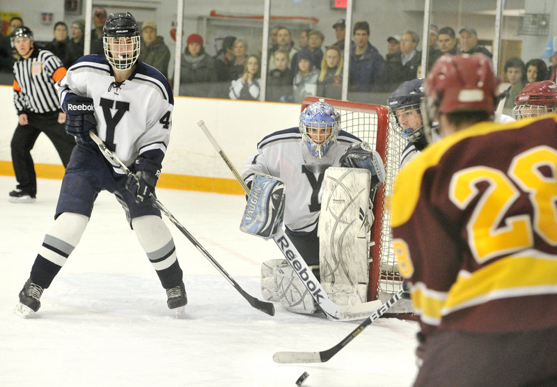 Yarmouth goalie Red DeSmith and Will Porter, left, keep their eyes on the puck as Curtis Guimond of Cape Elizabeth prepares to put a shot on net. Cape Elizabeth will meet Greely in the regional semifinals.
