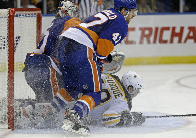 Chris Bourque of the Bruins lands beneath Islanders goalie Evgeni Nabokov and New York defenseman Andrew MacDonald in Tuesday night’s game at Uniondale, N.Y. The Bruins won 4-1 – their 16th win in the last 20 games against the Islanders.