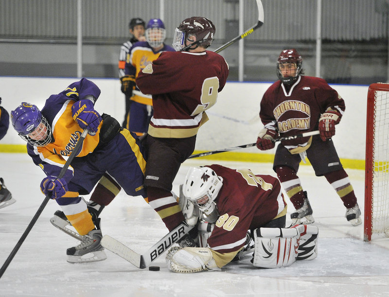 Thornton Academy goalie Andrew Huot dives to cover a loose puck Wednesday night in front of Patrick Sullivan of Cheverus during their Western Class A quarterfinal at the Portland Ice Arena. Cheverus will meet Scarborough in the semifinals Saturday at Lewiston.