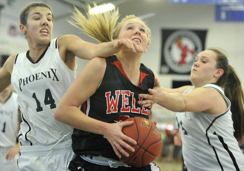 Sophie Lamb of Wells pulls in an offensive rebound between Spruce Mountain's Samantha Richards, left, and Emily Keene.