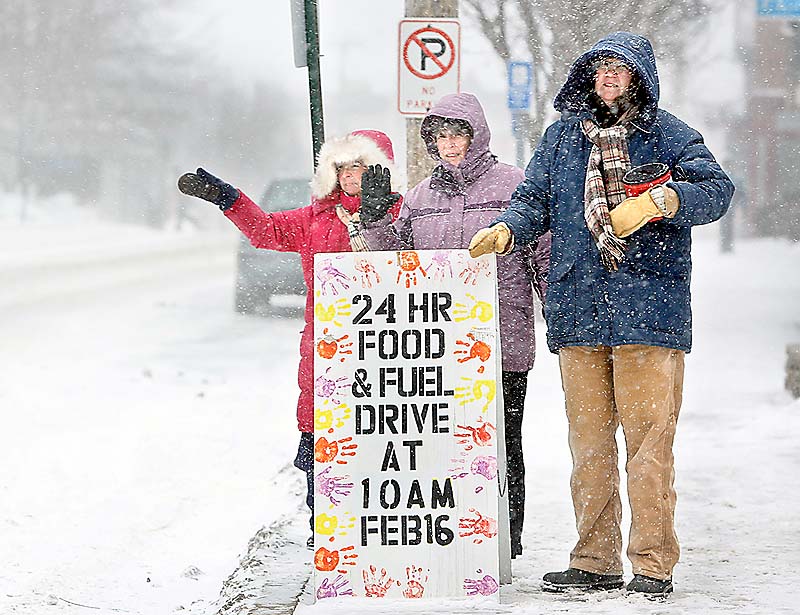 Patti Bruce, from left, Paula O’Brien and Sue Mack stand in front of the First Parish Church in Freeport and wave to passing cars Sunday during the 2013 Freeze Out, a 24-hour food and fuel drive to benefit a local food pantry and heating-assistance program.