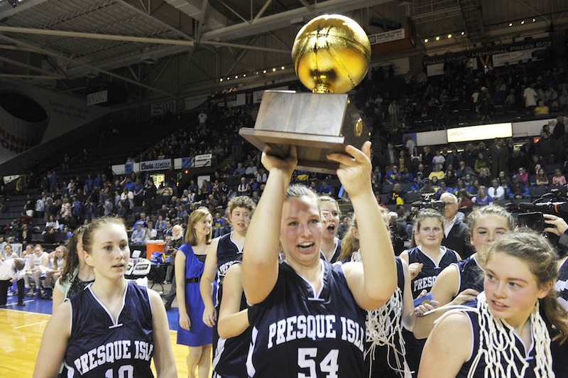 Presque Isle's Meredith Stewart, No. 54, carries the Class B state championship trophy following her teams win over the Lakers. It is Presque Isle's second straight title.