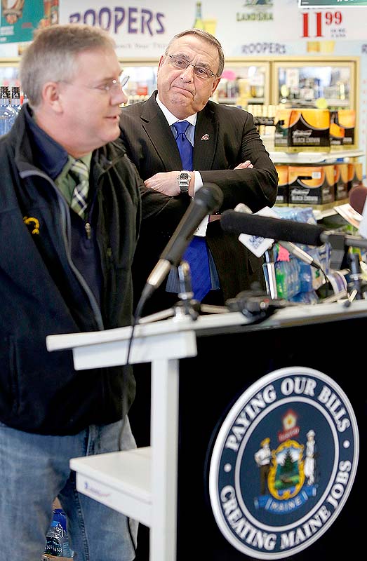 Gov. Paul LePage listens to Paul Landry, owner of Fish Bones American Grill, talk to the media about the governor's plan to pay back the hospital debt by leveraging future liquor sale revenue. The news conference took place at Roopers Beverage in Auburn on Friday.