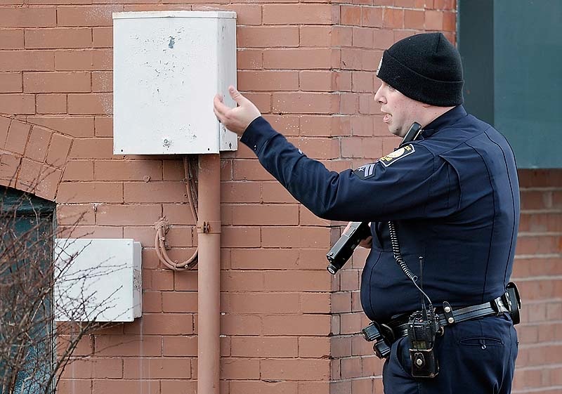 A police officer motions to a passerby to get out of the area as police surround the Lafayette Square apartment complex in Portland after gunshots were exchanged on the 6th floor on Friday, March 15, 2013.