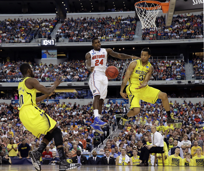 Michigan's Trey Burke (3) passes the ball to Tim Hardaway Jr. (10) in front of Florida's Casey Prather (24) during the second half of Sunday's NCAA college basketball tournament in Arlington, Texas.