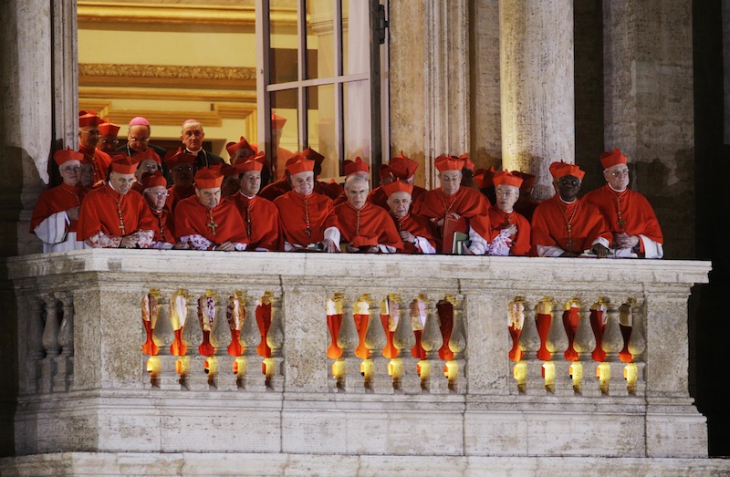 Cardinals watch as Pope Francis speaks to the crowd from the central balcony of St. Peter's Basilica at the Vatican, Wednesday, March 13, 2013. Cardinal Jorge Bergoglio, who chose the name of Francis, is the 266th pontiff of the Roman Catholic Church. (AP Photo/Andrew Medichini)