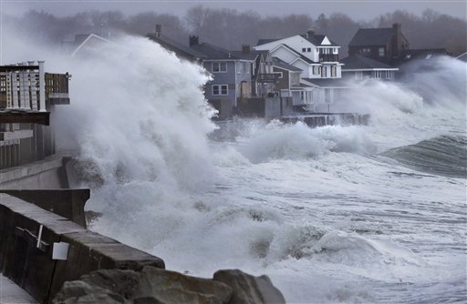 Ocean waves crash over a seawall and into houses along the coast in Scituate, Mass., on Thursday as a nor'easter bringing wind-whipped, wet snow hit Massachusetts.
