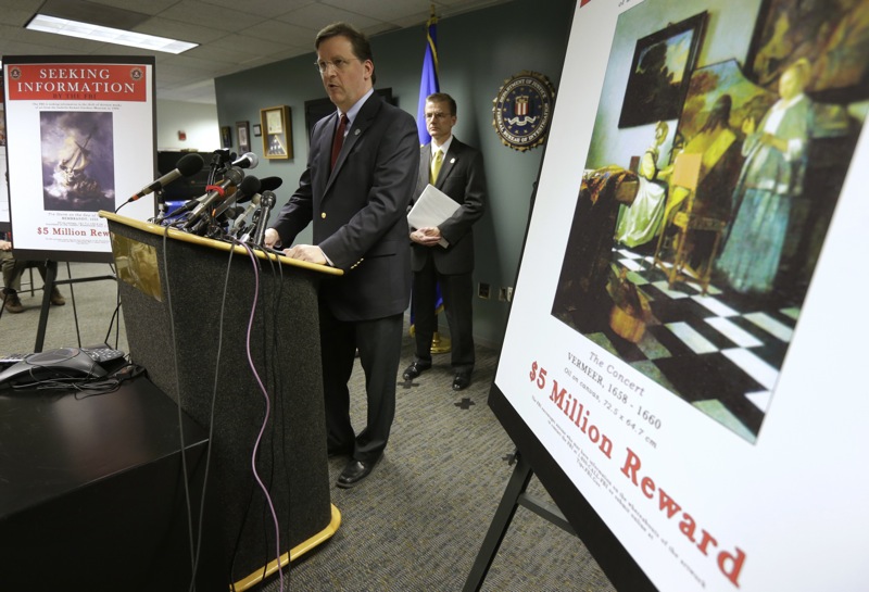 Anthony Amore, chief of security at the Gardner Museum, center, stands next to a poster that shows an image of a Vermeer painting and lists a reward, right, while facing reporters during a news conference at FBI headquarters in Boston, Monday, March 18, 2013. The FBI believes it knows the identities of the thieves who stole art valued at up to $500 million from Boston's Isabella Stewart Gardner Museum more than two decades ago. (AP Photo/Steven Senne)