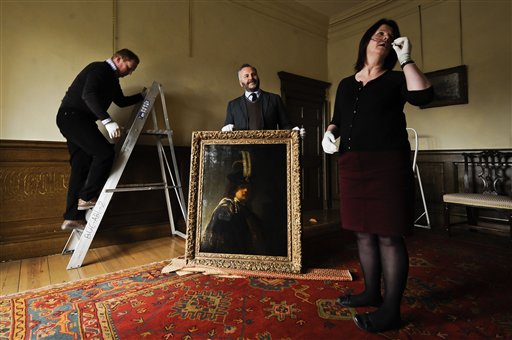 Buckland Abbey staff prepare to hang a recently confirmed self-portrait of Rembrandt.