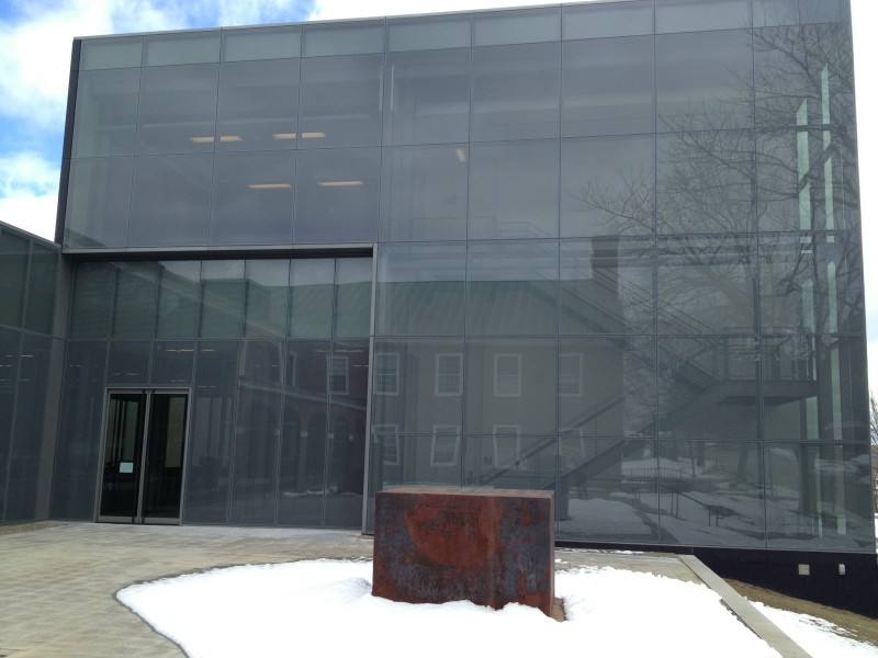 The exterior of the Alfond-Lunder Family Pavilion at the Colby College Museum of Art, with the college's older architecture reflected.